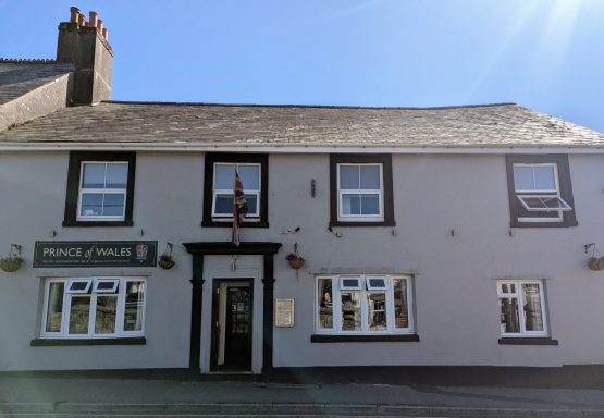 Front view of a two-storey pub with a slate roof and white window frames.