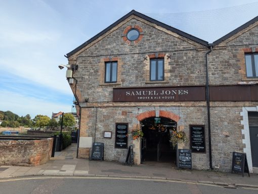 Stone building with a sign reading “Samwell House” and decorative planters.