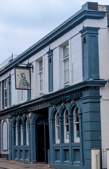 Historic blue and white building with arched windows and a hanging sign.