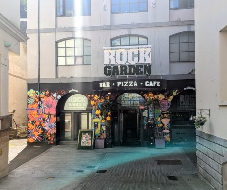Entrance to Rock Garden bar with colourful floral mural and outdoor seating area.