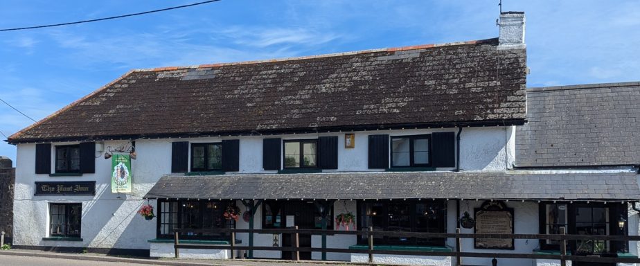 A traditional pub with a white exterior and a thatched roof against a clear blue sky.
