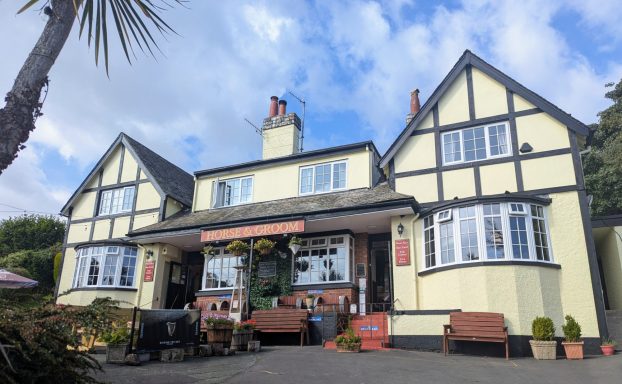 A charming, two-storey Tudor-style pub with a welcoming entrance and garden seating.