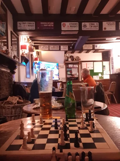 A chessboard in a pub setting, with drinks and patrons in the background.