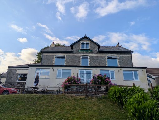 Large two-storey house with multiple windows, surrounded by greenery and flowers.