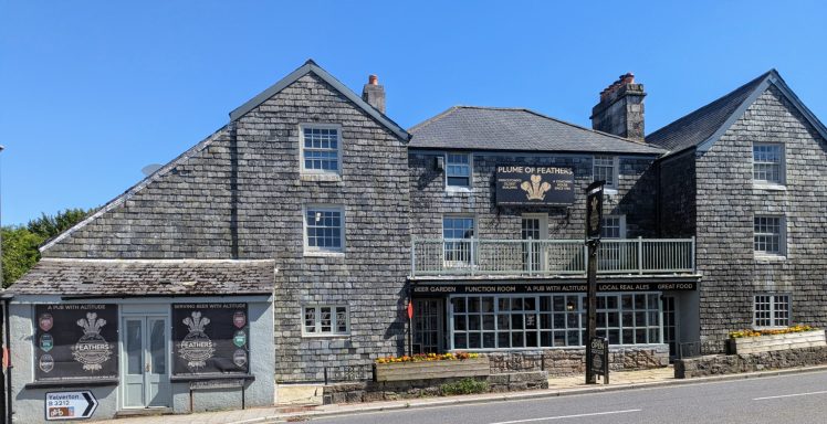 Stone building with multiple windows and a sign, set against a clear blue sky.