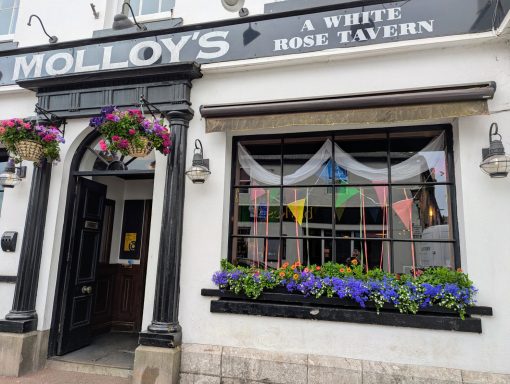Exterior of Molloy's A White Rose Tavern, featuring flowers and colourful bunting.