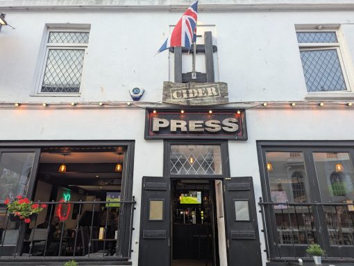 Exterior of a pub named "The Press" with a Union Jack flag and decorative lighting.