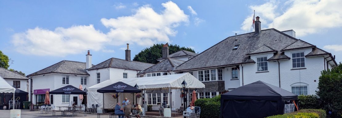 A cluster of white buildings with a blue sky and tents set up outside.