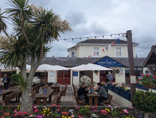 Outdoor dining area of a restaurant with tables, flowers, and a cloudy sky.