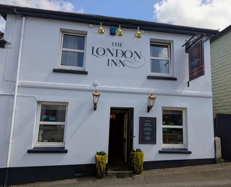 White building with the sign "The London Inn" and decorative outdoor lighting.