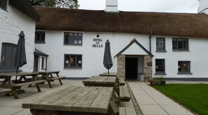 Traditional thatched cottage with outdoor seating and umbrellas.