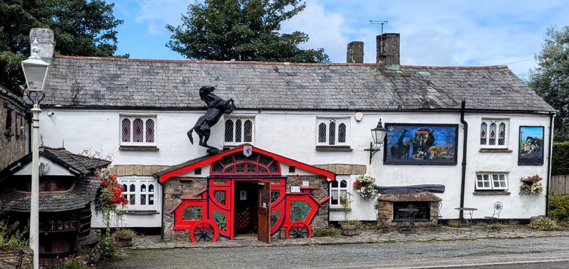 Traditional pub building with a red entrance and decorative paintings on the walls.