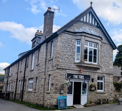 Stone building with a gabled roof, sign reading "The Inn" and a blue outdoor menu board.